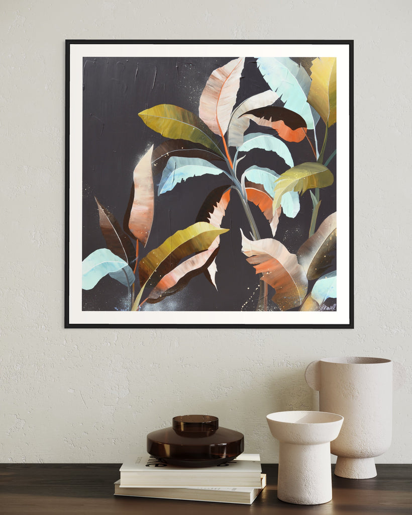 ‘Under the Canopy' Fine Art Print by Jasmine Marshall, framed in black/oak. Premium Giclée print features a palm tree on a brown background with abstract details. Displayed in a neutral home on a wooden shelf with books.