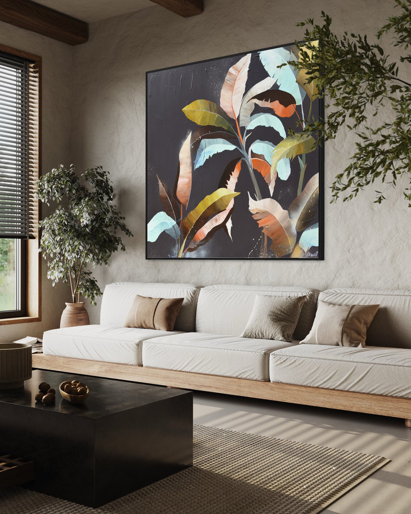 'Under the Canopy' original painting on a cotton canvas by Jasmine Marshall, framed in black/oak. Features a palm tree on a brown background with abstract details. Displayed in a neutral home with a white sofa and plants.