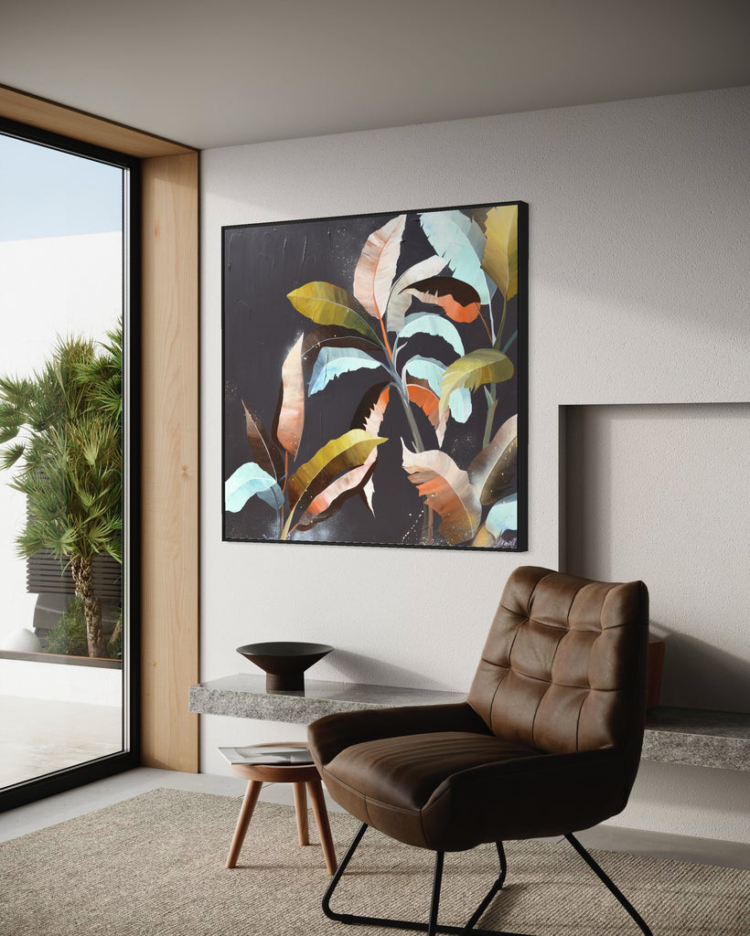 'Under the Canopy' original painting on a cotton canvas by Jasmine Marshall, framed in black/oak. Features a palm tree on a brown background with abstract details. Displayed in a neutral home interior with window overlooking the garden and a brown chair in front.