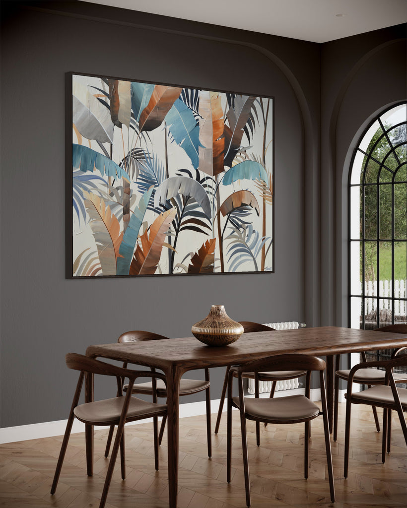 'Virgin Forest’ original painting on a cotton canvas by Jasmine Marshall, framed in black/oak. Features brown, blue, black leaves on a neutral background. Displayed in a kitchen with grey walls and a wooden dining table.